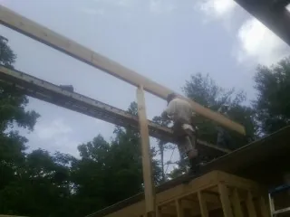 Carpenter setting a ridge beam over a new addition frame — Ice Dam Removal by Roofing Brothers in Bagdad