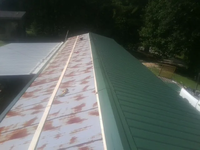 Old rusted panels beside newly installed green metal roofing — Wind Damage Roof Repair by Roofing Brothers in Bagdad