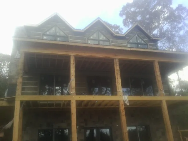 Dormers and porch framing on a large log home under construction — Roof Coating work by our crew in Bagdad