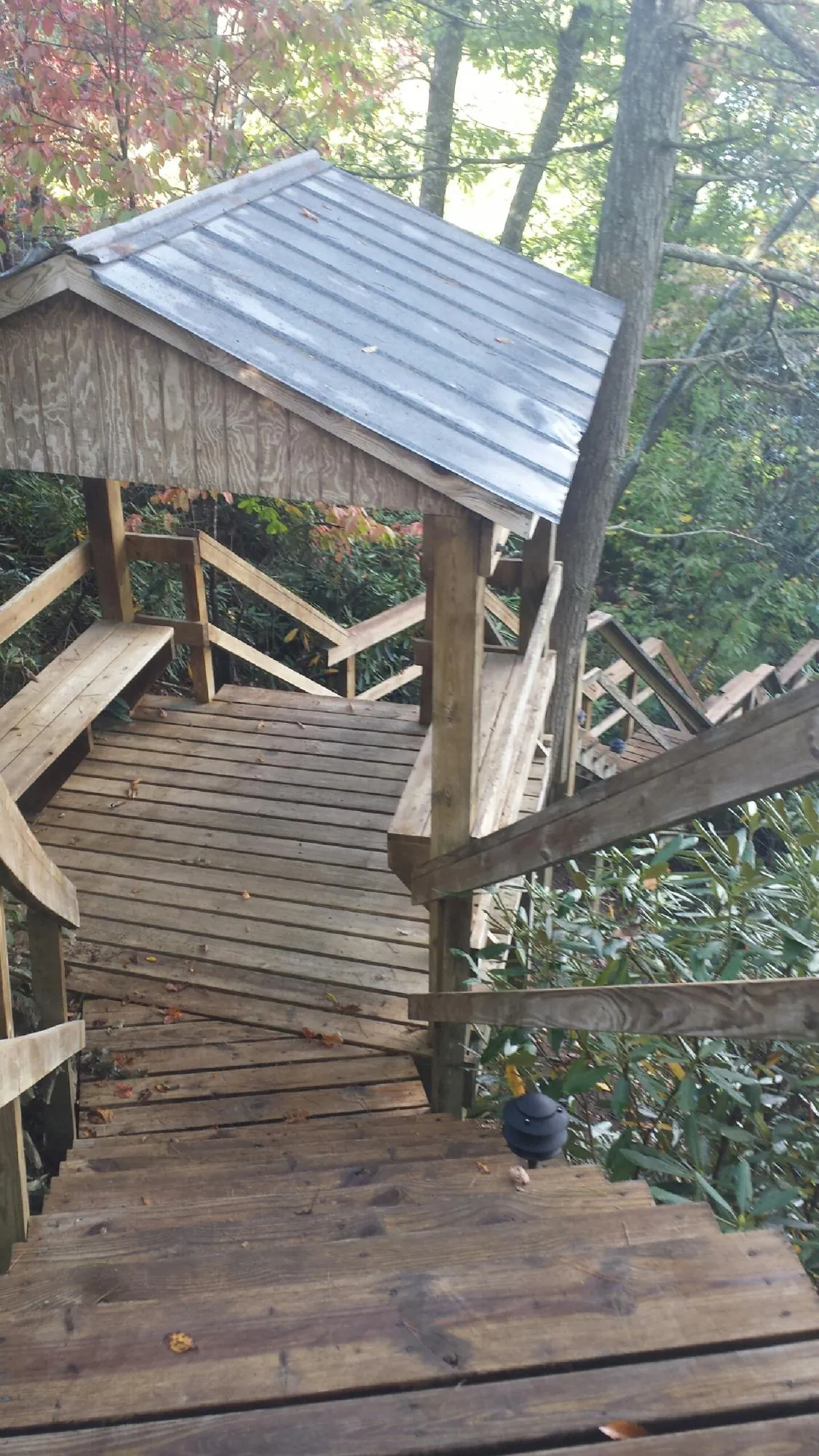Metal roofed shelter over wooden steps on a wooded walkway — Skylight Repair & Installation work by our crew in Bagdad